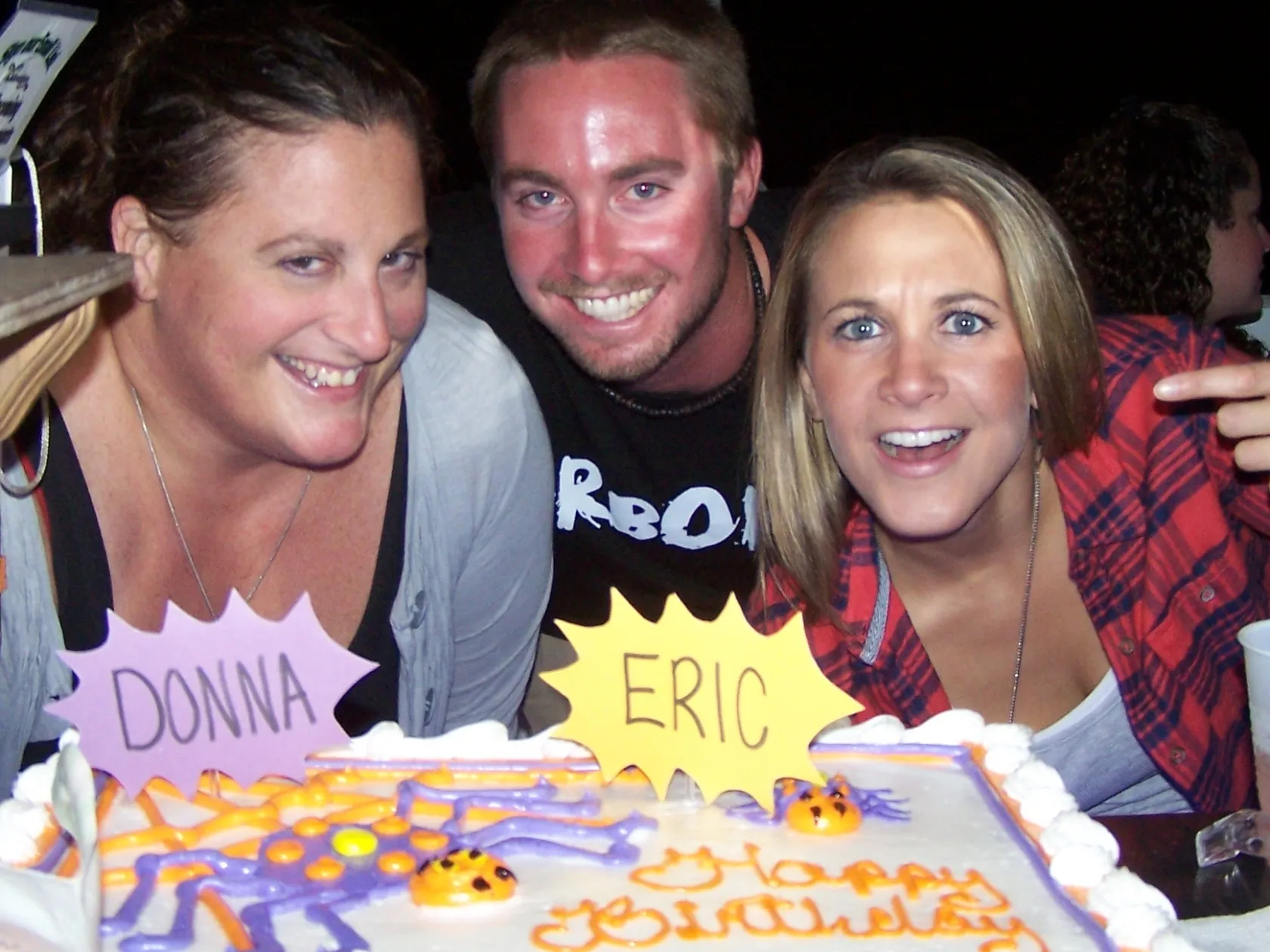 a group of people sitting at a table with a birthday cake