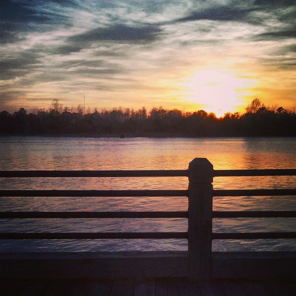 a bench in front of a sunset over a body of water