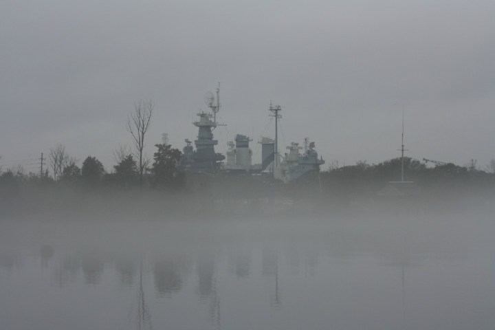 Battleship partially obscured by fog on a river.